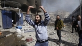18 ноября. Палестинцы зовут на помощь, стоя рядом с поврежденным после израильского авиаудара зданием в секторе Газа  (AP)
